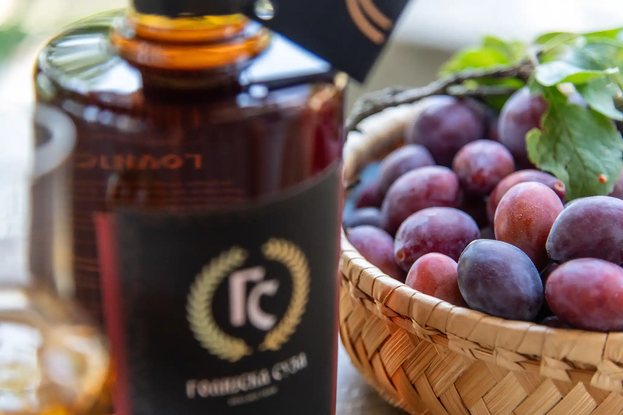 Premium plum brandy, with fresh plums in a basket behind the bottle.